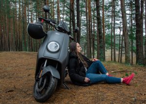 Una donna si rilassa nella foresta con il suo scooter elettrico ecologico