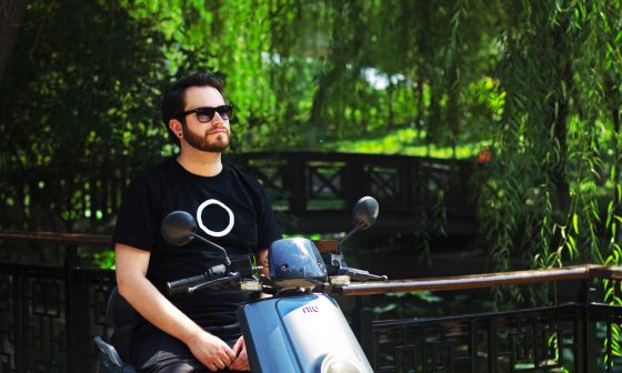 Hombre en un scooter eléctrico NIU al lado de un puente