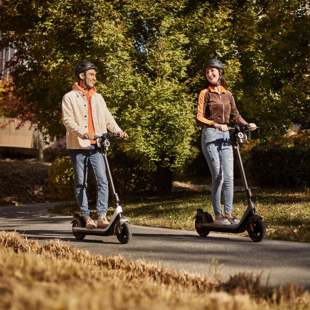 Two kick scooter riders in a park