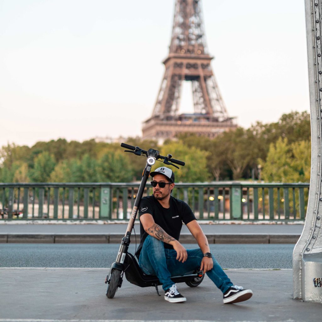 Man sitting on NIU KQi3 kick scooter in front of Eiffel Tower